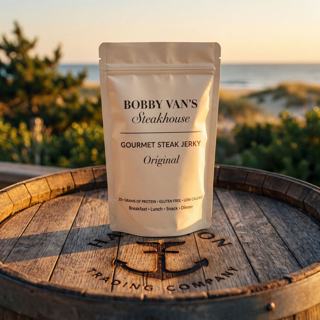 Bobby Van's Steakhouse Gourmet Steak Jerky pouch on a Hampton Trading Company barrel, oceanside at golden hour